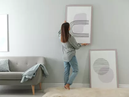 Vrouw die schilderij aan muur hangt